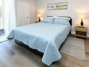 Een slaapkamer met een bed, twee nachtkastjes, een tapijt en een schilderij aan de muur.