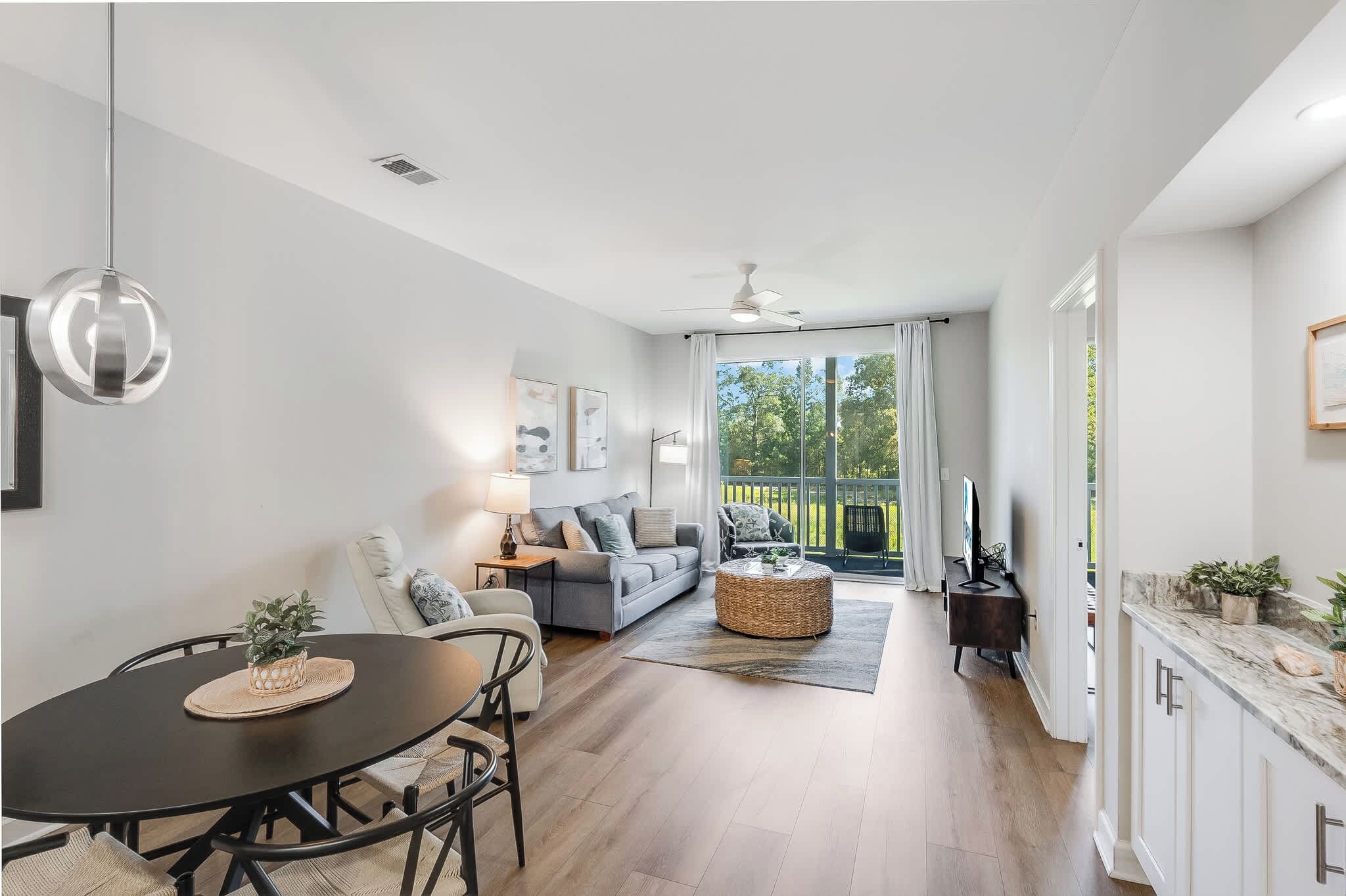 A modern living room with a dining table, sofa, and a view to the outside.