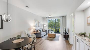 A modern living room with a dining table, sofa, and a view to the outside.