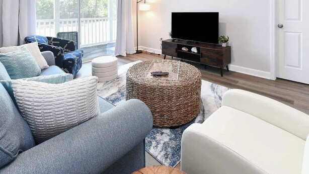 Ein Wohnzimmer mit einer Sofagarnitur, einem Couchtisch und einem Fernseher auf einem Lowboard.