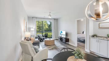 Una sala de estar moderna con un sofá, sillones, una mesa de comedor y un televisor.