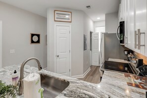A modern kitchen with a marble countertop, stainless steel sink, and a built-in oven. - Large 2BR Unit with Pool Access, River Oaks Golf (Myrtle Beach)