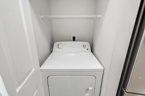 A compact, white, wall-mounted washer and dryer unit with a control panel featuring various settings. - Large 2BR Unit with Pool Access, River Oaks Golf (Myrtle Beach)