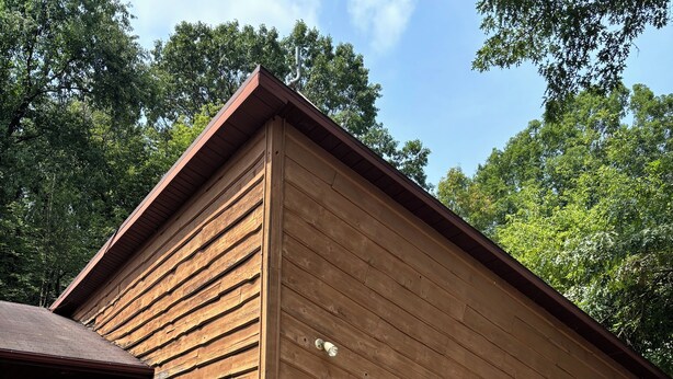 Een laag gebouw met een garage, een welkomstbord en een kleine tuin.