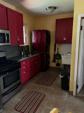 A compact kitchen with red cabinets, a microwave, a stove, and a refrigerator. - Charming 1-bedroom apartment, near the Airport, great for travel connections (Nassau)
