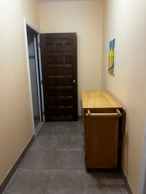 A hallway with a wooden door, a small table, and a painting on the wall. - Charming 1-bedroom apartment, near the Airport, great for travel connections (Nassau)