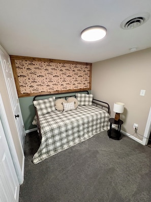 Ein Schlafzimmer mit einem Bett, einem Kopfteil mit Fischmuster, einer Nachttischlampe und einer Tür.