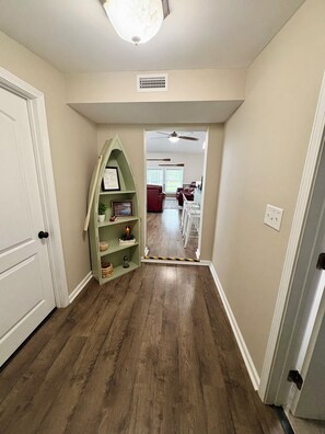 A hallway with wooden flooring, a green shelf unit, and a ceiling fan. - The Pungo Perch: Waterfront Retreat with Boat Lift, Fishing & Pets Welcome (Belhaven)
