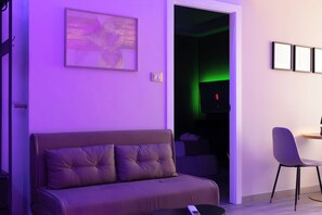 A modern living room with a sofa, a chair, and a flat-screen TV. - VELARIS LUXURY SUITE & SPA - Self-Check-In (Bologna)