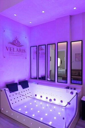 A room with a large massage table, multiple mirrors, and a sign reading 'VELARIS LUXURY SUITE & SPA'. - VELARIS LUXURY SUITE & SPA - Self-Check-In (Bologna)
