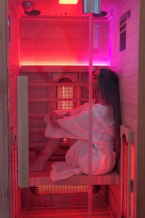 Eine Sauna mit Holzvertäfelung, einer Sitzbank und einer Person, die darauf sitzt.
