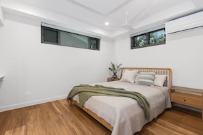 Ein Schlafzimmer mit einem Bett, einem Nachttisch, einer Wand-Klimaanlage und einem Deckenventilator.