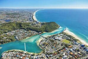 Vue aérienne d’une ville côtière, avec une plage, une zone résidentielle densément peuplée et une vaste étendue d’eau.
