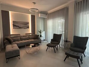 Ein modernes Wohnzimmer mit einer Eckcouch, einem runden Couchtisch und zwei Sesseln.