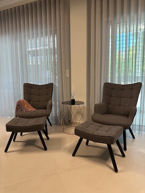 A modern living room with two armchairs, a small round table, and sheer curtains. - Parkside Residence (Vironas)