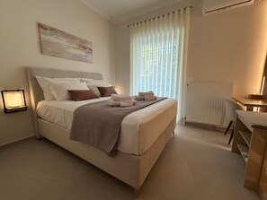 Habitación de hotel con cama, mesita de noche, lámpara, radiador y ventana con cortinas.