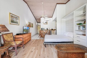 Un dormitorio con una cama, un escritorio, una silla, un televisor y una estantería.