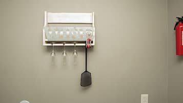 A wall-mounted wine rack with three glasses and a corkscrew.