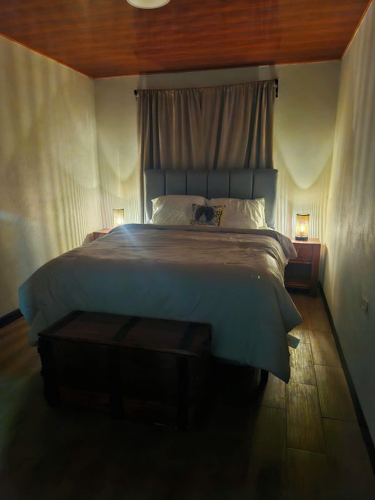 Un dormitorio con cama, lámparas de noche y un banco de madera.