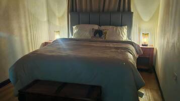 Un dormitorio con cama, lámparas de noche y un banco de madera.