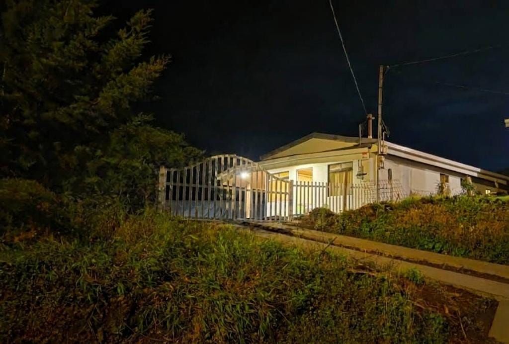 A building with a gated entrance, a covered porch, and a pathway leading to the entrance.