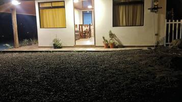 Una casa de dos pisos con un comedor visible y un pequeño porche con plantas en macetas.