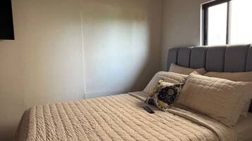Une chambre à coucher avec un lit, une fenêtre et un téléviseur fixé au mur.
