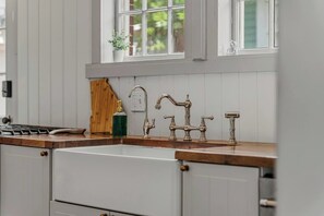 A kitchen with a wooden countertop, a white sink, and a vintage-style faucet. - The Arch House – 4BR – Midtown – Game Loft + Fire Pit (Columbus)