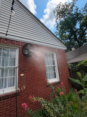 A red brick house with two windows, a fan, and a hanging light fixture. - The Arch House – 4BR – Midtown – Game Loft + Fire Pit (Columbus)