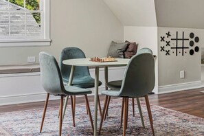 A dining area with a round table, four chairs, and a chessboard. - The Arch House – 4BR – Midtown – Game Loft + Fire Pit (Columbus)