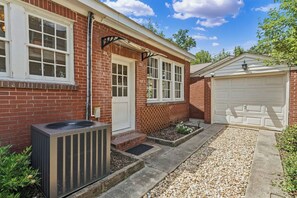 A residential property with a brick exterior, a garage, and an air conditioning unit. - The Arch House – 4BR – Midtown – Game Loft + Fire Pit (Columbus)