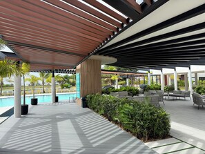 Un espacio al aire libre techado con piscina, asientos y vegetación.
