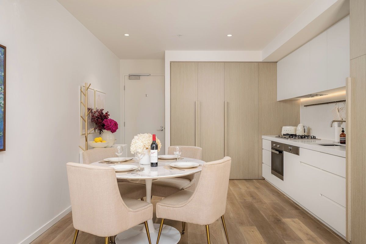 A modern kitchen with white cabinets, a dining table set for four, and a small island with a sink.