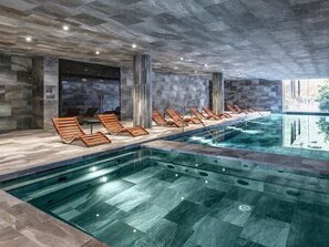 Ein moderner Poolbereich im Innenbereich mit Liegestühlen und klarem Wasser.