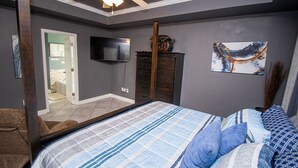 Ein Schlafzimmer mit einem Bett, einem Fernseher, einem Deckenventilator, einem Schminktisch und einem Gemälde an der Wand.