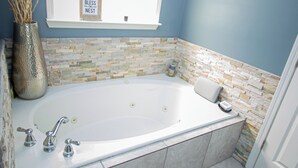 Ein Badezimmer mit einer Badewanne, einem Fenster, einem Handtuchhalter und einer Dekovase.