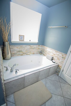 Une salle de bain avec une baignoire, une fenêtre, un porte-serviettes et un vase décoratif.