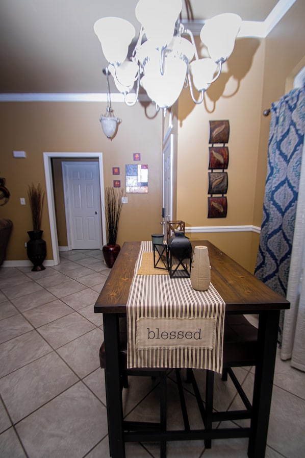 Un comedor con una mesa de madera, sillas, una lámpara de araña y una pared con paneles decorativos.