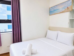 Habitación de hotel con una cama, un cuadro de una playa y una ventana con cortinas.