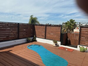 A rooftop deck with a blue mat, wooden fence, and potted plants. - Beautiful Frida heart beach house, (Tijuana)