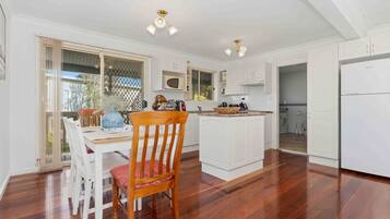 A kitchen with white cabinets, a wooden dining table, and a chair.