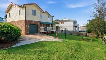 A two-story house with a front porch, a garage, and a fenced backyard.