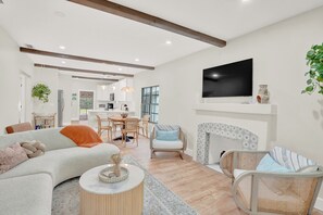 A modern living room with a sofa, chairs, a coffee table, a fireplace, and a television. - Lovely Fully Remodeled 4-bedroom house in the heart of West Palm Beach! (West Palm Beach)