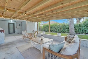 An outdoor patio with a wooden ceiling, a table and chairs, a sofa, and a view of a garden. - Lovely Fully Remodeled 4-bedroom house in the heart of West Palm Beach! (West Palm Beach)