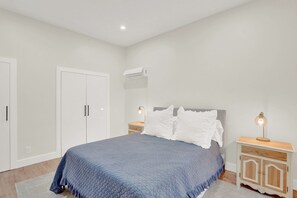 A bedroom with a bed, nightstands, a wardrobe, and an air conditioning unit. - Lovely Fully Remodeled 4-bedroom house in the heart of West Palm Beach! (West Palm Beach)