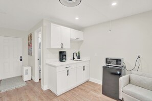 A modern kitchen with white cabinetry, a coffee maker, a microwave, and a small refrigerator. - Lovely Fully Remodeled 4-bedroom house in the heart of West Palm Beach! (West Palm Beach)