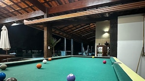 A pool table with balls, a wooden ceiling, and a white wall. - Vrbo Property (Moeda)