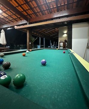 Una mesa de billar con bolas, techo de madera y pared blanca.