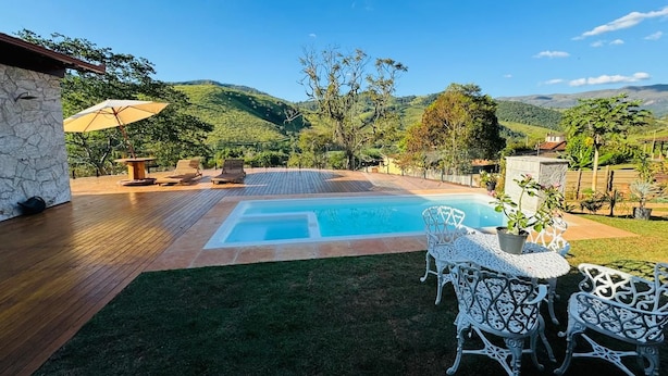 A backyard with a swimming pool, outdoor furniture, and a view of the hills. - Vrbo Property (Moeda)