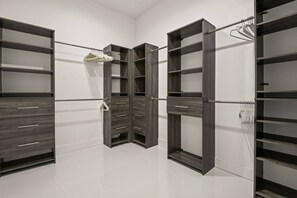 Ein begehbarer Kleiderschrank mit offenen Regalen, Schubladen und Kleiderstangen.
